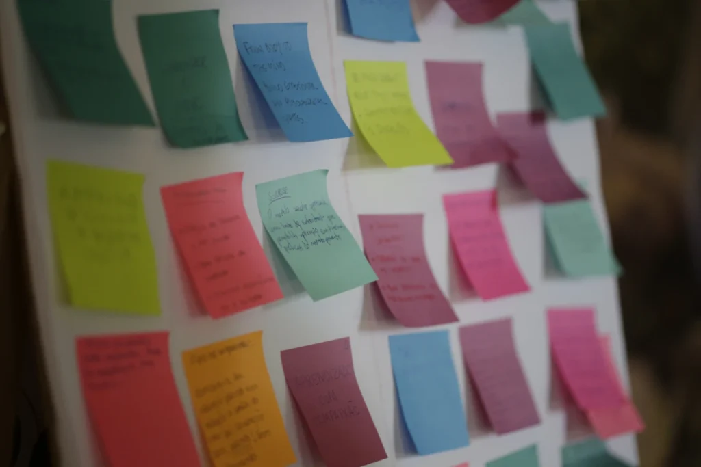 Close-up of a wall covered in colourful Post-it notes featuring handwritten mindfulness messages, with other blurred notes referencing Dragon Academy teachings in the background